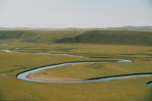 A winding river flowing through a wide grassy floodplain